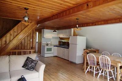 a living room with a couch and a table and a kitchen at Chalet du barrage in East Broughton Station