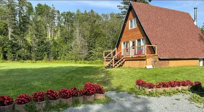 a house with red flowers in front of it at Chalet du barrage in East Broughton Station