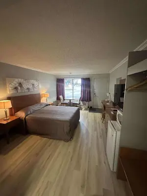 a bedroom with a bed and a desk and a room with at Hôtel Motel Le Voyageur in Saint-Georges
