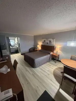 a hotel room with a bed and a table and chairs at Hôtel Motel Le Voyageur in Saint-Georges