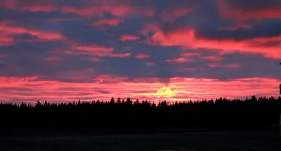 a sunset over a field with trees under a red sky at Maison du Mont-Mégantic spa à l'année in Lac-Mégantic