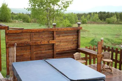 a wooden fence with a table and chairs on a deck at Maison du Mont-Mégantic spa à l'année in Lac-Mégantic