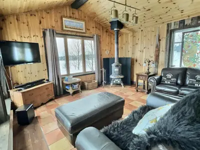 a living room with a couch and a flat screen tv at Maison du Mont-Mégantic spa à l'année in Lac-Mégantic