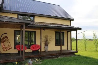 a house with red seats on a deck at Maison du Mont-Mégantic spa à l'année in Lac-Mégantic