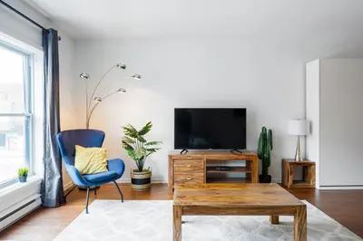 a living room with a tv and a blue chair at Suite Mont-Royal by MTLVacationRentals in Montréal