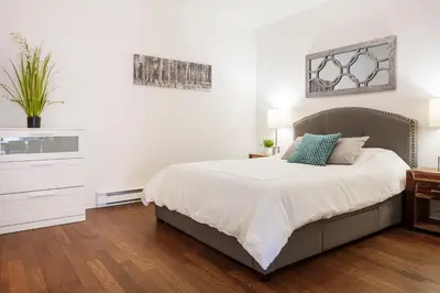 a white bedroom with a bed and a dresser at Suite Mont-Royal by MTLVacationRentals in Montréal