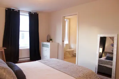 a bedroom with a bed and a mirror and a window at Suite Mont-Royal by MTLVacationRentals in Montréal