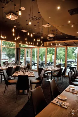 a dining room with tables and chairs and windows at Hotel du Lac Champlain in Venise-en-Québec