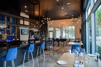 a restaurant with blue chairs and tables and a bar at Hotel du Lac Champlain in Venise-en-Québec