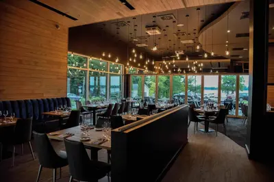a dining room with tables and chairs and windows at Hotel du Lac Champlain in Venise-en-Québec