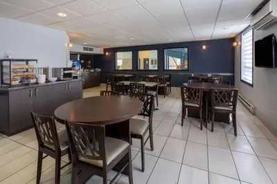 a dining room with tables and chairs and a kitchen at Super 8 by Wyndham Lachenaie/Terrebonne in Terrebonne