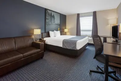 a hotel room with a bed and a couch at Super 8 by Wyndham Lachenaie/Terrebonne in Terrebonne