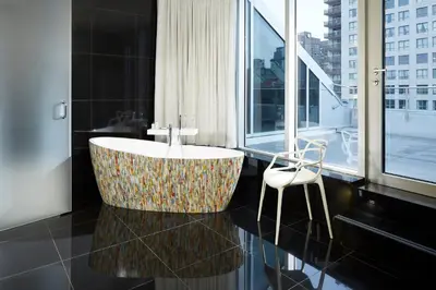 a bathroom with a bath tub and a chair at Le Mount Stephen in Montréal