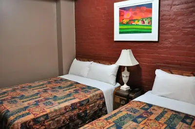 a hotel room with two beds and a lamp at Hotel Ste-Catherine in Montréal