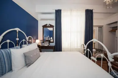 a bedroom with a white bed and a blue wall at Manoir Sherbrooke in Montréal