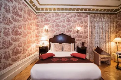 a bedroom with a large bed with pink wallpaper at Manoir Sherbrooke in Montréal