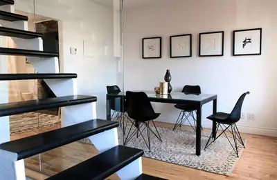 a dining room with a table and black chairs at L'Hotel Particulier Griffintown in Montréal