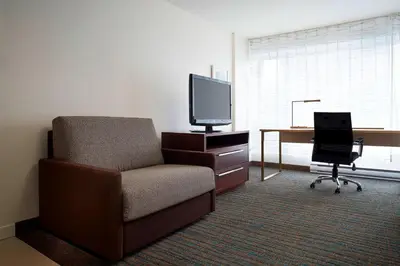 a living room with a chair and a desk with a television at Residence Inn by Marriott Montréal Downtown in Montréal