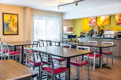 a restaurant with tables and chairs and a kitchen at Comfort Inn South Shore in Boucherville