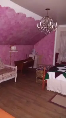 a bedroom with purple walls and a bed and a chandelier at Gite Agricole Les Lilas in Saint Wenceslas