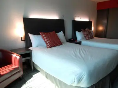 a hotel room with two beds and a chair at Grand Hotel Times Sherbrooke in Sherbrooke