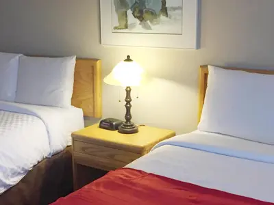 a bedroom with two beds and a lamp on a night stand at Auberge du Grand Lac in Magog-Orford