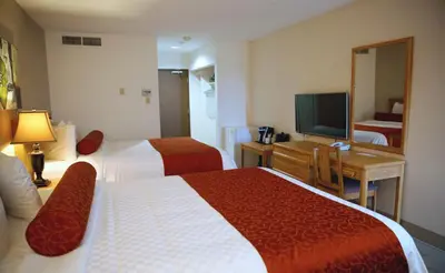 a hotel room with two beds and a television at Auberge du Grand Lac in Magog-Orford