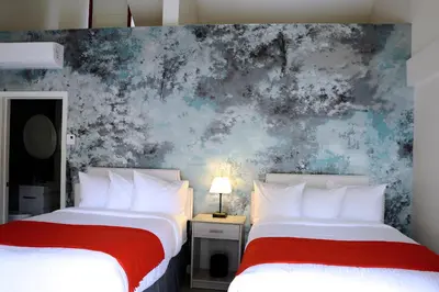 two beds in a room with a wall mural at Auberge du Grand Lac in Magog-Orford