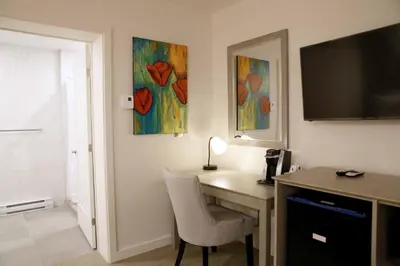 a room with a desk with a television and paintings at Auberge du Grand Lac in Magog-Orford