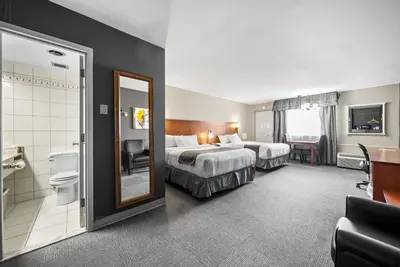a hotel room with two beds and a bathroom at Hotel-Motel Coconut in Trois-Rivières