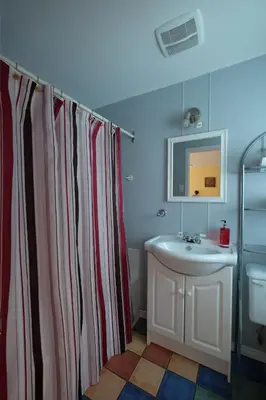 a bathroom with a red and white shower curtain and a sink at Motel Canadien in Trois-Rivières
