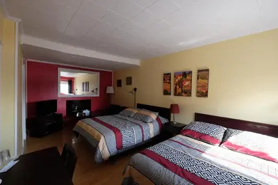 a hotel room with two beds and a mirror at Motel Canadien in Trois-Rivières