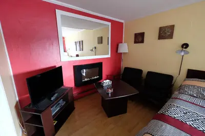 a room with a bed and a television and a mirror at Motel Canadien in Trois-Rivières