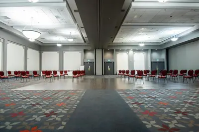 a large room with red chairs and tables and windows at Delta Hotels by Marriott Sherbrooke Conference Centre in Sherbrooke
