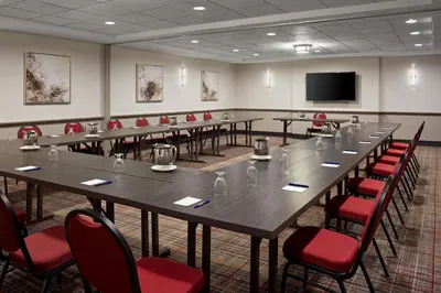 a conference room with long tables and red chairs at Delta Hotels by Marriott Sherbrooke Conference Centre in Sherbrooke