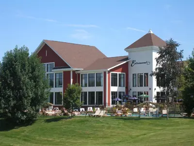 a building with chairs and tables in front of it at Estrimont in Magog-Orford