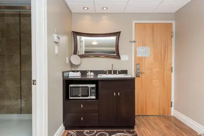 a kitchen with a sink and a microwave in a room at Hotel & Suites Le Dauphin Drummondville in Drummondville