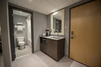 a bathroom with a sink and a toilet and a mirror at Hotel & Suites Le Dauphin Drummondville in Drummondville