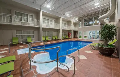 a large indoor pool with chairs and a slide in a building at Hotel & Suites Le Dauphin Drummondville in Drummondville