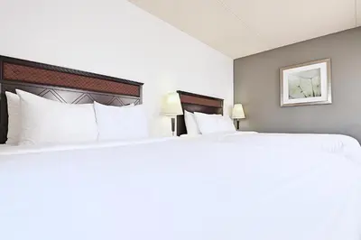 two beds in a hotel room with white pillows at LELUX Hotel in Montréal