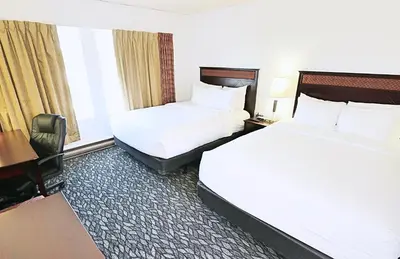 a hotel room with two beds and a desk at LELUX Hotel in Montréal