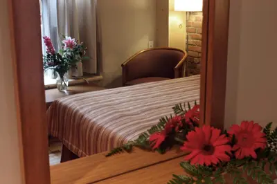 a mirror reflecting a bedroom with a bed and flowers at Hotel Quartier des Spectacles in Montréal