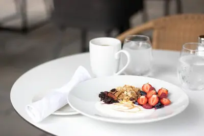 a plate of food on a table with a cup of milk at Hotel Mortagne in Boucherville