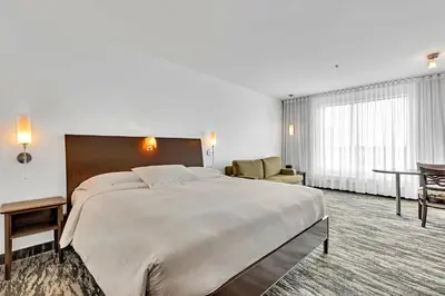 a hotel room with a large bed and a table at Hotel Mortagne in Boucherville