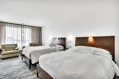 a hotel room with two beds and a chair at Hotel Mortagne in Boucherville
