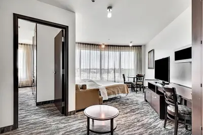 a bedroom with a bed and a desk and a television at Hotel Mortagne in Boucherville