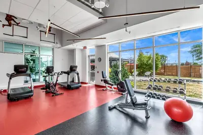 a gym with a lot of exercise equipment and large windows at Hotel Mortagne in Boucherville