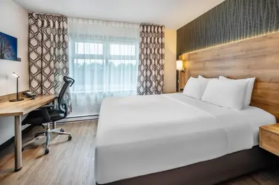 a hotel room with a large bed and a desk at Quality Suites in Drummondville