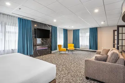 a hotel room with a bed and two chairs and a tv at Quality Suites in Drummondville