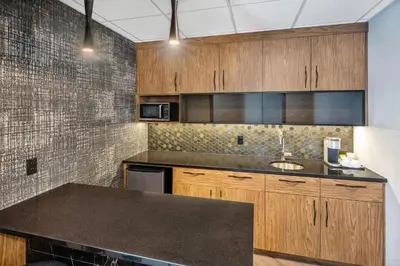 a kitchen with wooden cabinets and a sink at Quality Suites in Drummondville